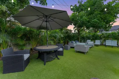 a table and chairs with an umbrella on the grass at Steps to Sand! - Wellness Escape - Coastal Retreat in Fort Lauderdale