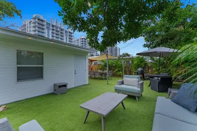 a backyard with a lawn with chairs and an umbrella at Steps to Sand! - Wellness Escape - Coastal Retreat in Fort Lauderdale