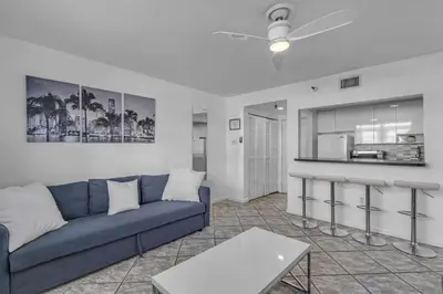 a living room with a blue couch and a kitchen at 1 BLOCK FROM OCEAN 1 Bedroom in South Beach Collins Avenue in Miami Beach