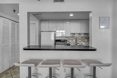 a kitchen with a counter with four bar stools at 1 BLOCK FROM OCEAN 1 Bedroom in South Beach Collins Avenue in Miami Beach