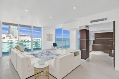 a living room with a white couch and large windows at Oceanview 3BR Penthouse | Pool + Beach Access in Hallandale Beach