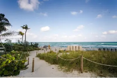 a sandy beach with a fence and the ocean at Oceanview 3BR Penthouse | Pool + Beach Access in Hallandale Beach