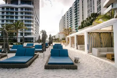 a beach with blue lounge chairs and buildings at Oceanview 3BR Penthouse | Pool + Beach Access in Hallandale Beach