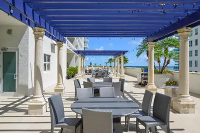 a patio with tables and chairs with the ocean in the background at Luxury Suite | Sauna, Pool & Resort Access in Miami