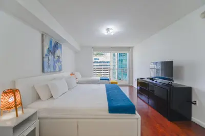 a bedroom with a large white bed and a television at Luxury Suite | Sauna, Pool & Resort Access in Miami