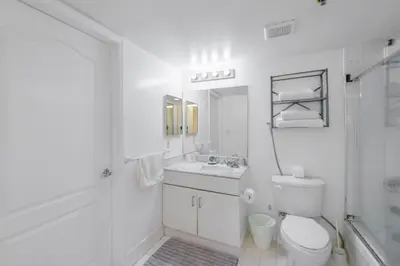 a white bathroom with a toilet and a sink at Luxury Bayview Condo | Pool, Gym & Skyline Views in Miami