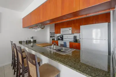 a kitchen with a white refrigerator and wooden cabinets at Luxe 2BD Unit | W Sauna, Pool & Gym access in Miami