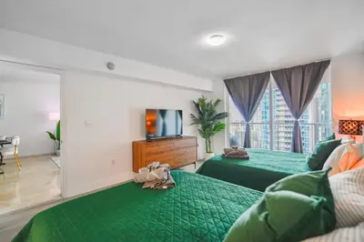 a bedroom with two green beds and a tv at Luxury 2BD Condo | Sauna, Pool & Resort Access in Miami