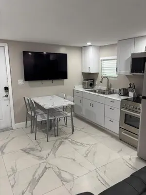 a kitchen with a table with chairs and a television at Peace and Tranquility awaits in Miami Gardens
