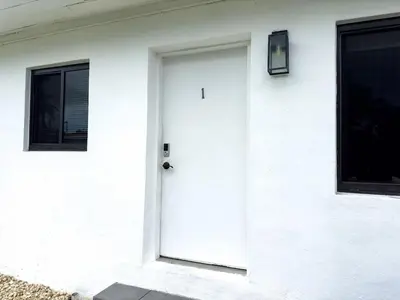 a white door on a white house with two windows at Unit 1 Cozy 1BR Apt with Parking in Miami