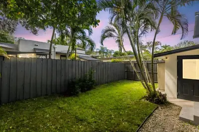 a backyard with a fence and a green yard at Casa Palma in Miami