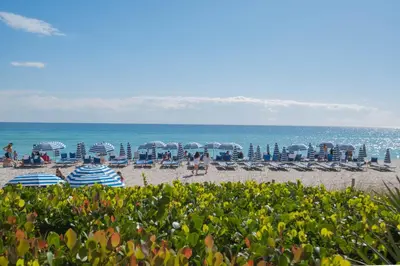 a beach with chairs and umbrellas and the ocean at Ocean View 3 BDR Condo Pool Gym Private Balcony in Hallandale Beach