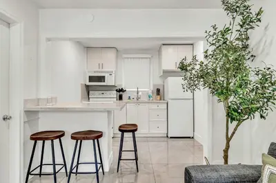 a white kitchen with two stools and a counter at Bright 1BR Getaway Victoria Park Las Olas Nearby in Fort Lauderdale