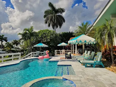 a swimming pool with chairs and a pink flamingo at The Bird-2 blocks to beach-Heated Pool-Hot Tub in Fort Lauderdale