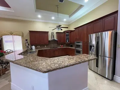 a kitchen with wooden cabinets and a stainless steel refrigerator at Miami Mansion for Groups Sleeps 12 in Kendale Lakes