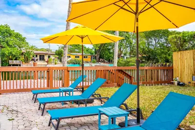 a group of blue chairs and an umbrella at Waterfront Pool Home Games, 10 min to Beach in Fort Lauderdale