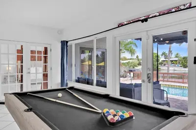 a pool table in a living room with a pool ball at Waterfront Pool Home Games, 10 min to Beach in Fort Lauderdale
