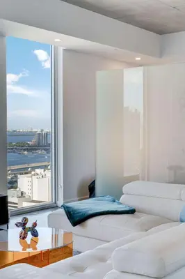 a living room with white furniture and a large window at Vibrant Downtown Haven with Rooftop Pool & Parking in Miami
