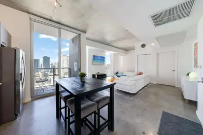 a kitchen with a table and a living room with a view at Vibrant Downtown Haven with Rooftop Pool & Parking in Miami