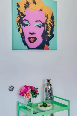 a painting of a woman on a wall above a glass table at Vibrant Downtown Haven with Rooftop Pool & Parking in Miami