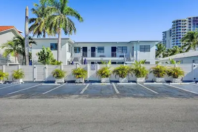 a white building with palm trees and a white fence at Desoto 2 Bedrooms in Hollywood