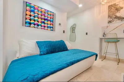 a bedroom with a bed with a blue blanket on it at Boardwalk Steps from the Beach in Miami Beach