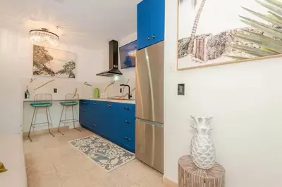 a kitchen with blue cabinets and a vase on a stool at Boardwalk Steps from the Beach in Miami Beach