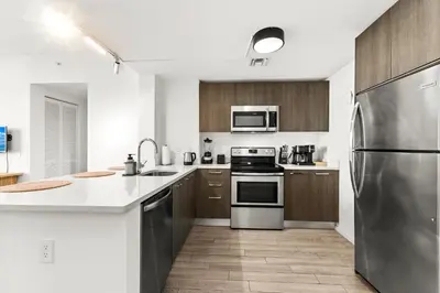 a kitchen with stainless steel appliances and wooden cabinets at Prime Downtown Stay 2BR- Parking Included -Near Bayside & Cruise Port in Miami