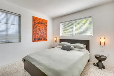 a bedroom with a large bed and two windows at Tropical backyard with pool 10 min from Miami Beach! in Miami