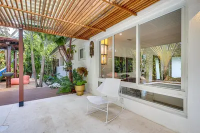 a porch with a white chair on a patio at Tropical backyard with pool 10 min from Miami Beach! in Miami