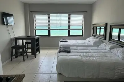 a bedroom with two beds and a desk and a window at Casablanca Beachfront with full kitchen in Miami Beach