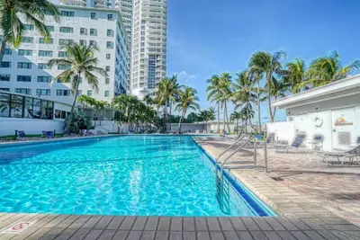 a swimming pool with palm trees and buildings at Casablanca Beachfront with full kitchen in Miami Beach