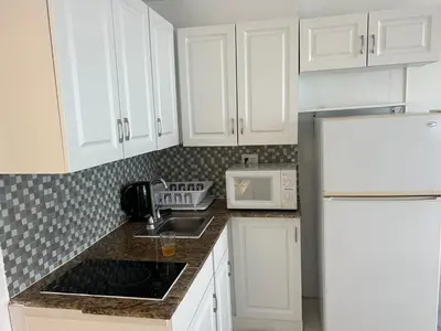 a kitchen with white cabinets and a white refrigerator at Casablanca Beachfront with full kitchen in Miami Beach