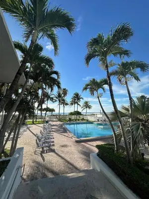 a resort with a pool and palm trees and chairs at Casablanca Beachfront with full kitchen in Miami Beach