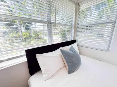 a bed with two pillows in a room with windows at Family Pool Retreat 3 BR House for more than 8 Guests in Hollywood
