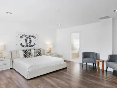 a white bedroom with a bed and two chairs at Villa Zenora in Miami