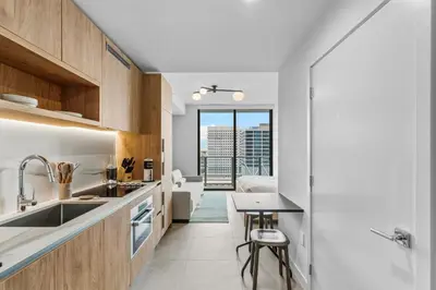 a kitchen with wooden cabinets and a table with a view at Modern Studio w Skyline Views by Bayfront Park in Miami