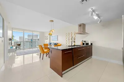 a kitchen and dining room with orange chairs and a table at Luxury Waterfront W Hotel Condo Brickell Skyline Views in Miami