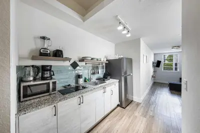 a kitchen with white cabinets and a stainless steel refrigerator at Art Deco Gem by the Beach King Bed & Parking in Miami Beach