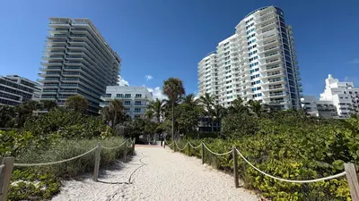 a beach with a fence and some tall buildings at Steps from Ocean Art Deco 1BR & Free Parking in Miami Beach