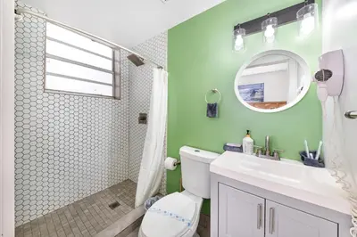 a bathroom with a white toilet and a green wall at Art Deco Escape Steps to Ocean & Free Parking in Miami Beach