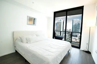 a white bed in a room with a large window at Downtown Miami 2BR Retreat - Walk to Bayside & Port - Sleeps 6 in Miami