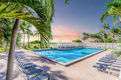a swimming pool with chairs and palm trees at Beachfront Apartment in Miami Beach at the Casablanca Hotel in Miami Beach