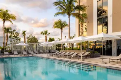 a swimming pool with chairs and umbrellas next to a building at Blueground Coral Gables pool wd nr Vizcaya MIA-125 in Miami