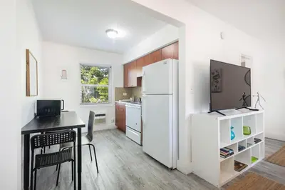 a white kitchen with a table and a refrigerator at B08 10 MIN FROM MIAMI BEACH, Studio, Miami Design District & Wynwood in Miami