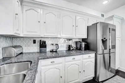 a kitchen with white cabinets and a stainless steel refrigerator at Spanish 5 Bedroom Pool House Minutes to the Beach in Hollywood