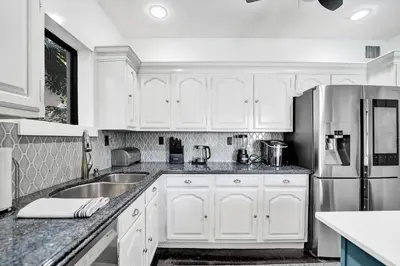 a kitchen with white cabinets and a stainless steel refrigerator at Spanish 5 Bedroom Pool House Minutes to the Beach in Hollywood
