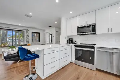 a kitchen with white cabinets and a blue chair in it at Cute 3 Bedroom 2 Bathroom Pool Home in Hollywood