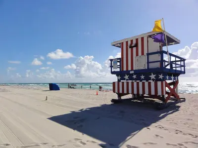 a lifeguard tower on a beach with the american flag at The Azure Terrace Loft in Miami Beach