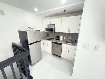 a kitchen with white cabinets and a refrigerator at The Azure Terrace Loft in Miami Beach